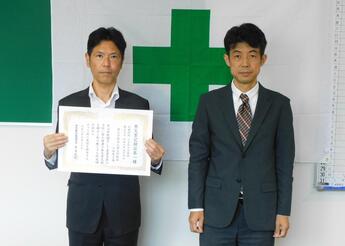 賞状を持つ工場長の画像
