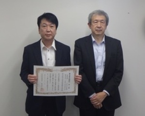 賞状を持つ工場長の画像